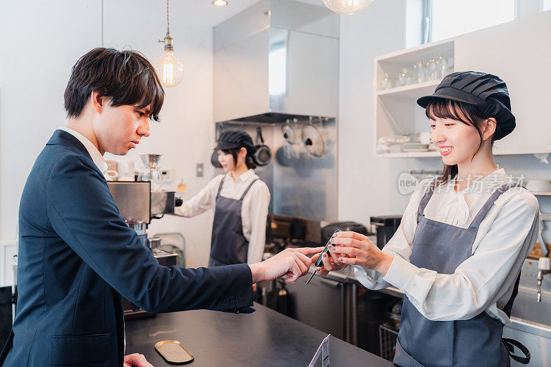 A businessman making a credit card payment at a café